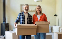 Older couple enjoying moving into new home holding boxes 2722955187