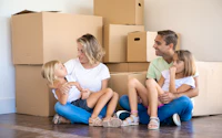 Parents talking with daughter on mother hands happy family sitting on floor with children mom dad and girls surrounded with cardboard boxes in new home mortgage relocation and moving day 1820955836