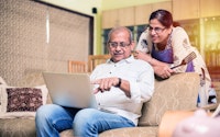 Senior indian couple with laptop sitting on sofacouch at home 1346789036